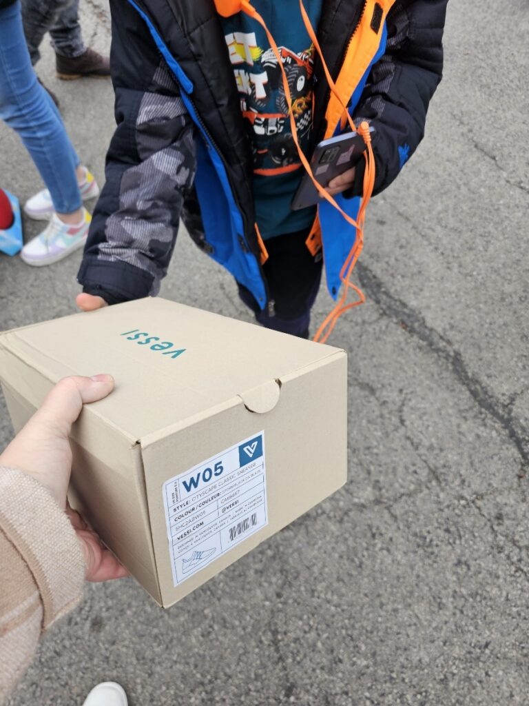 Photo of a child receiving a new pair of shoes from a local nonprofit thanks to GiveNKind and Vessi shoes.